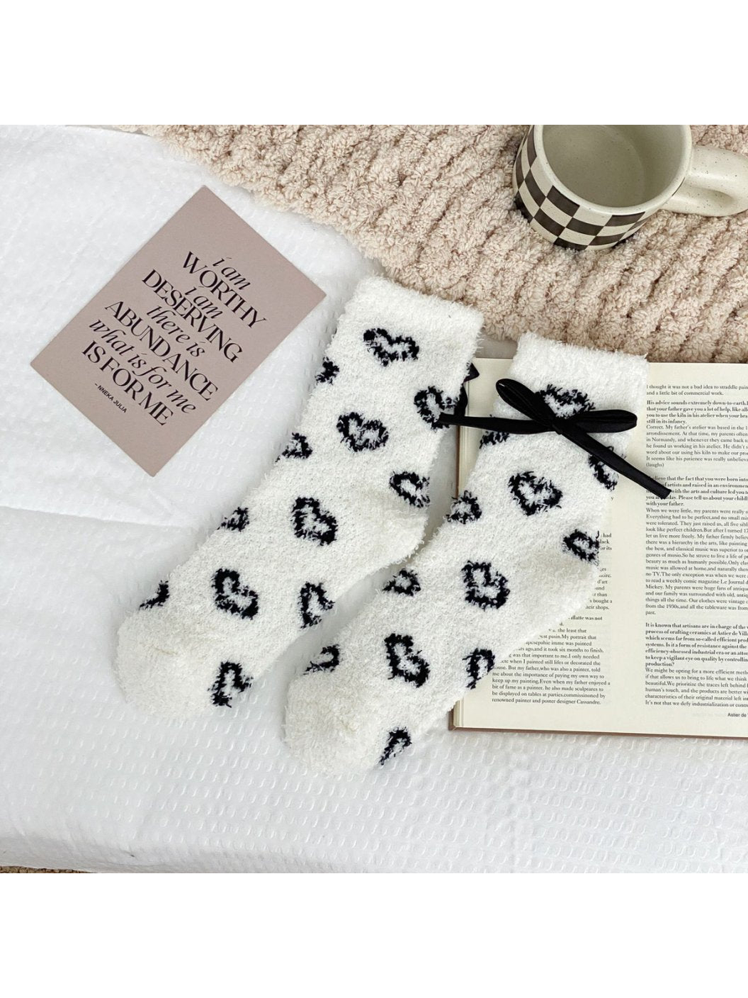 White fuzzy socks with outlined black hearts and a black ribbon bow