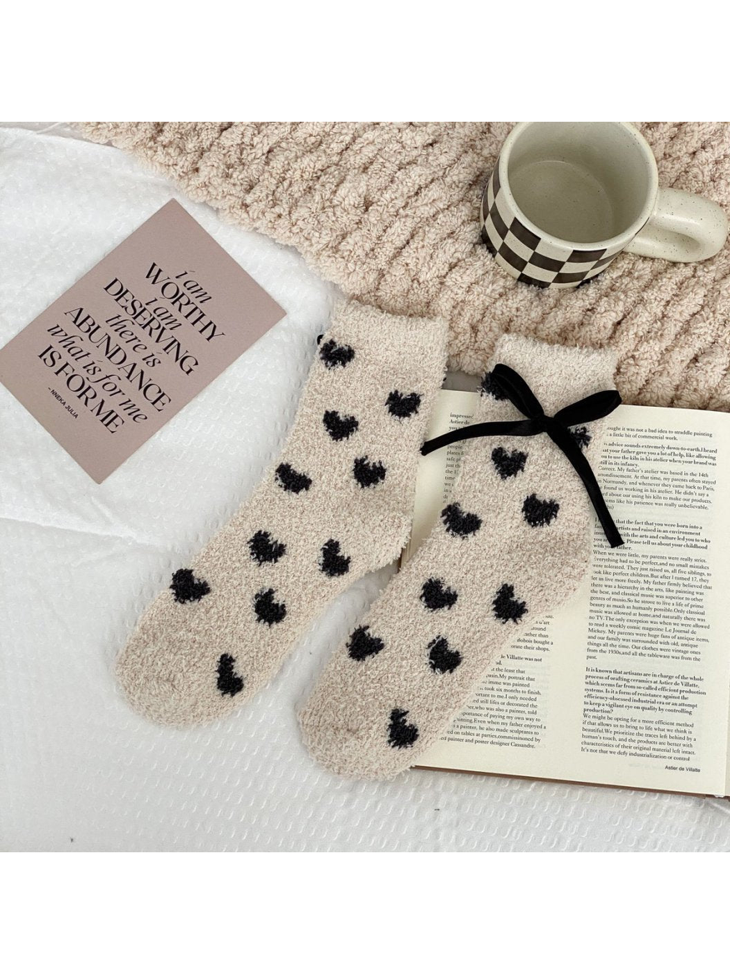 Beige fuzzy socks with small dark hearts and a black ribbon bow