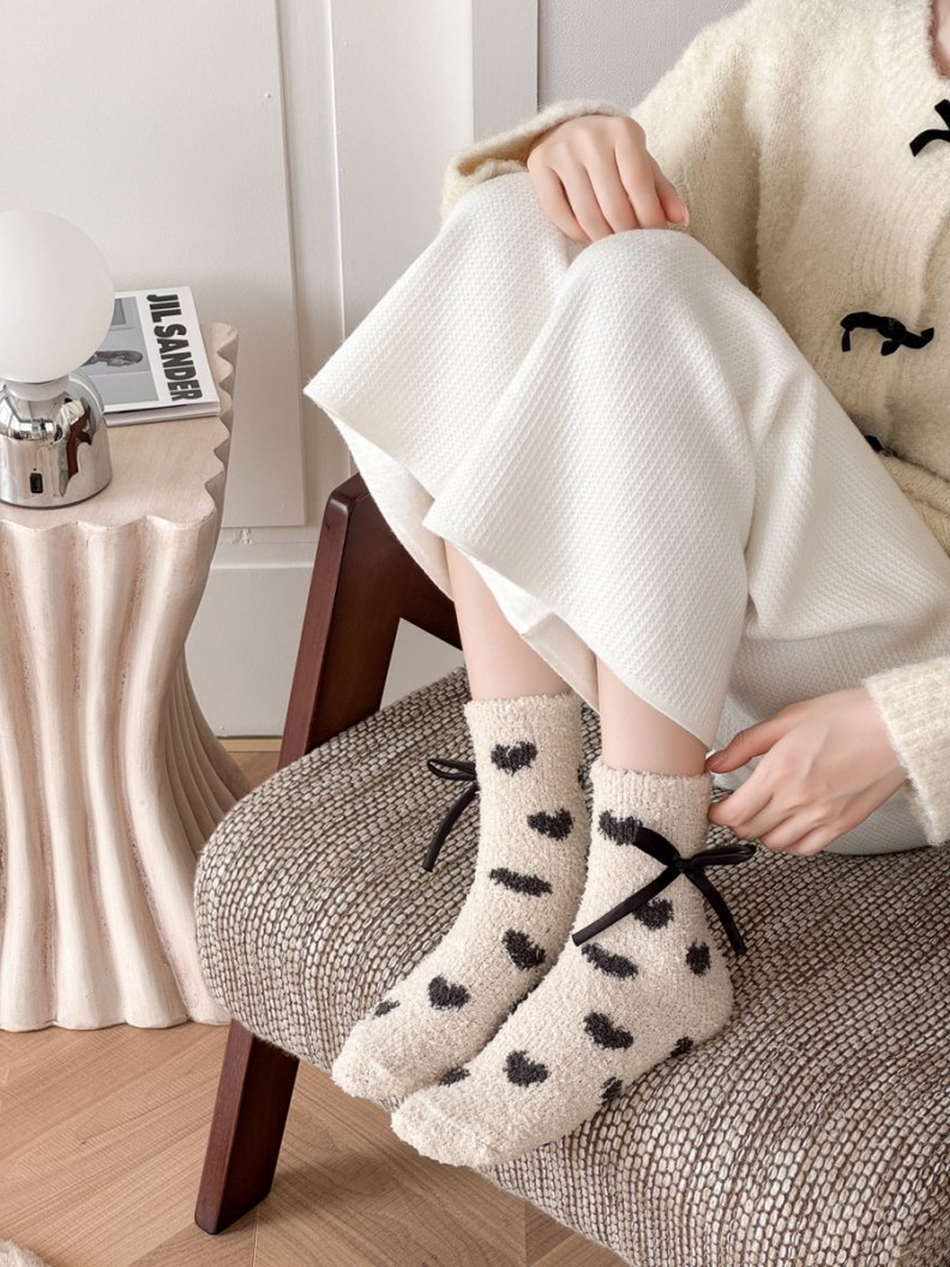 Beige fuzzy heart-pattern socks worn while seated