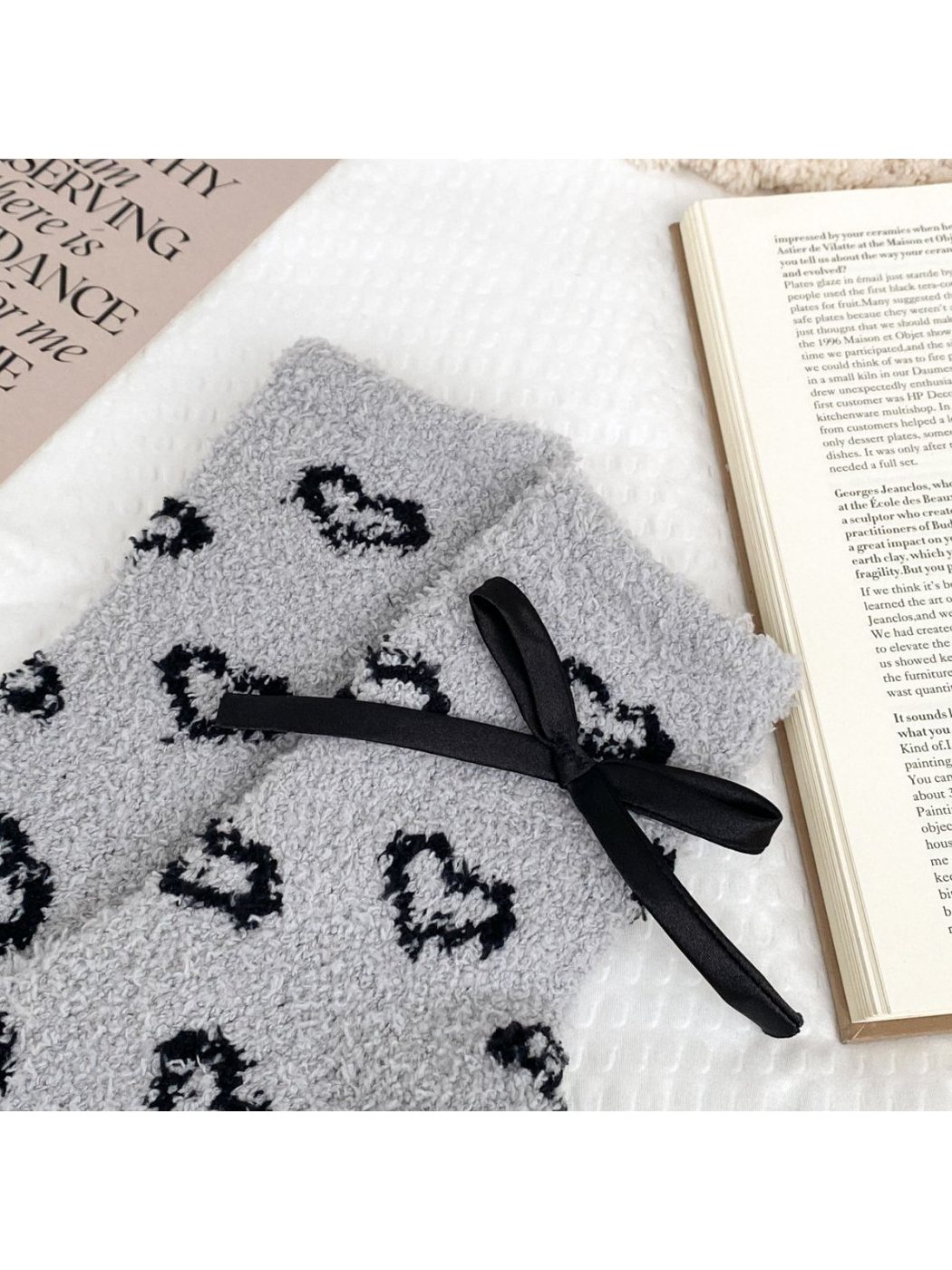 Close-up of light gray fuzzy socks with outlined hearts and a ribbon bow