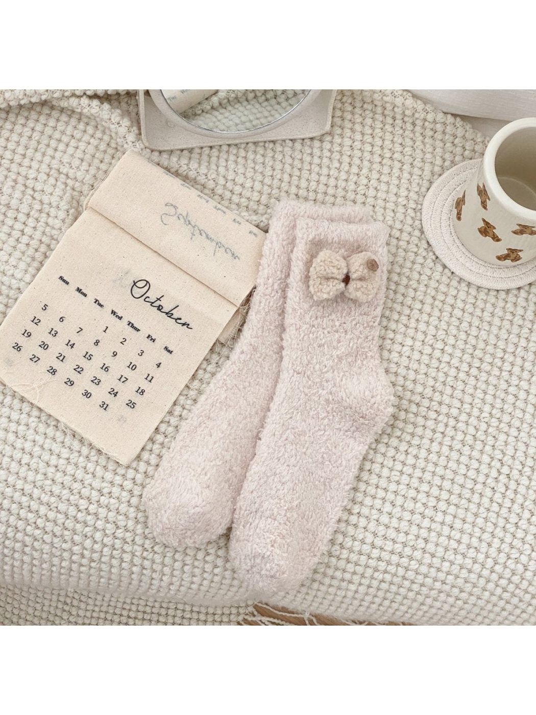 Pale blush fuzzy crew socks with a cream bow applique