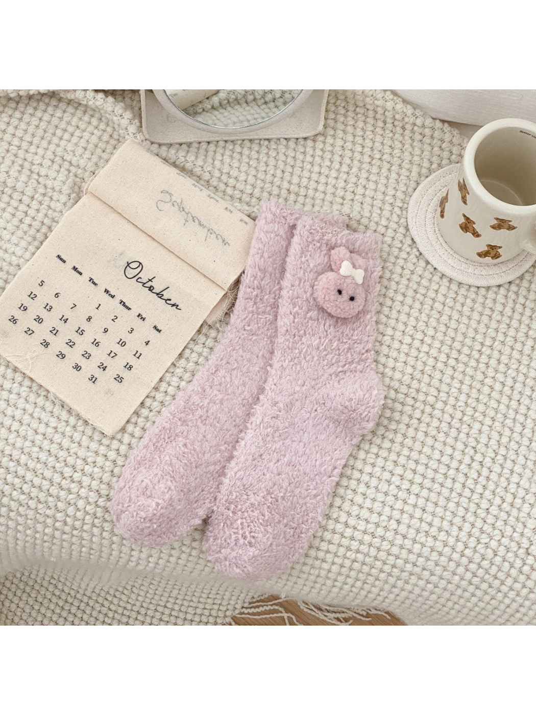 Light pink fuzzy crew socks with a pink animal-face applique