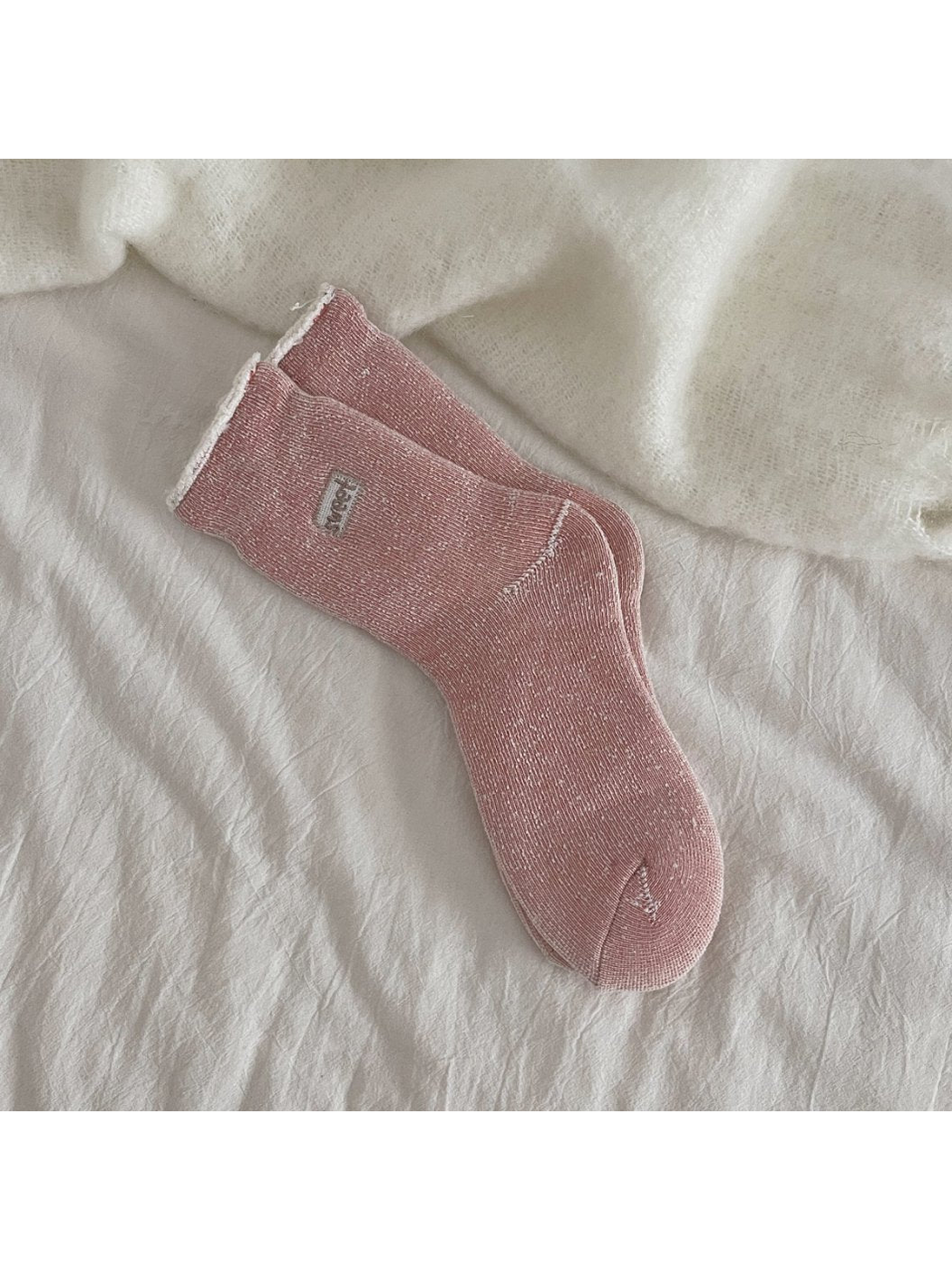 Dusty pink ribbed crew socks with a rolled cuff and small label patch