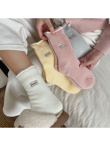 Ivory socks worn with lined clogs beside pink, yellow and gray pairs