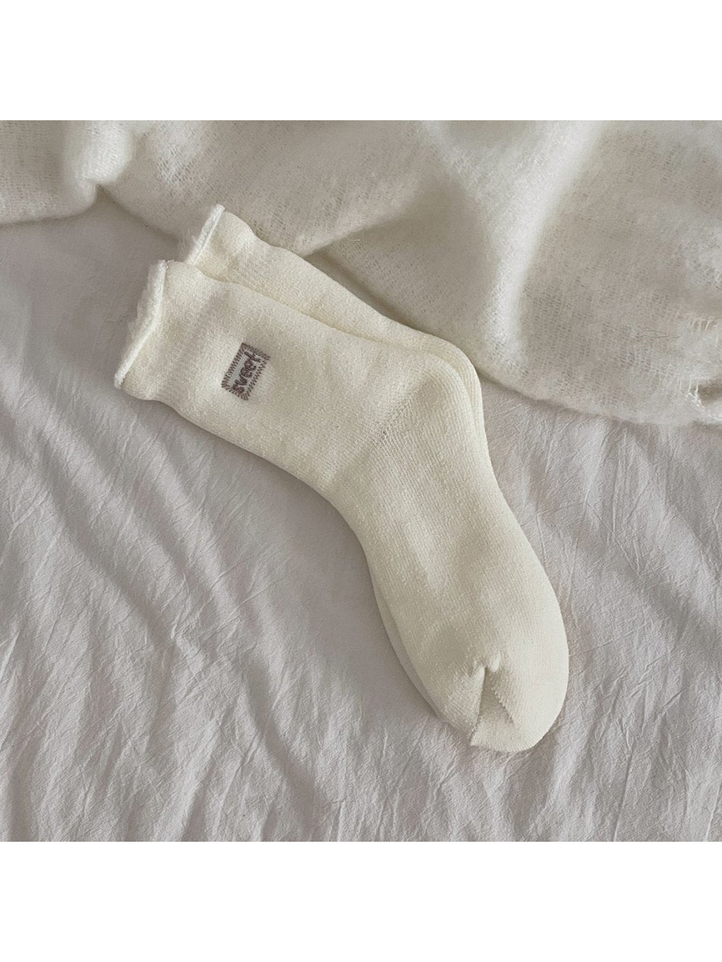 Ivory ribbed crew socks with a rolled cuff and small label patch