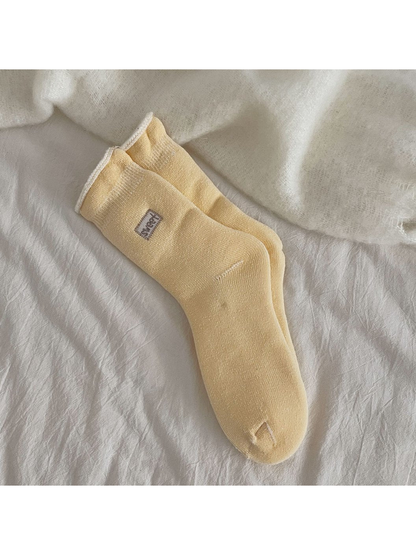 Yellow ribbed crew socks with a rolled cuff and small label patch
