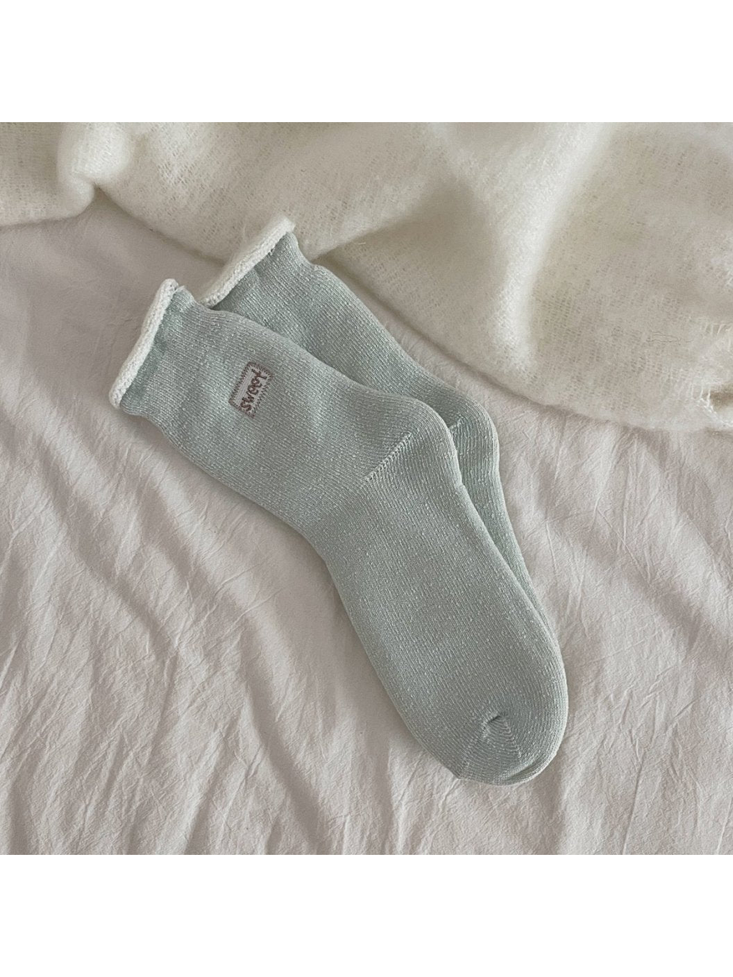 Light blue ribbed crew socks with a rolled cuff and small label patch