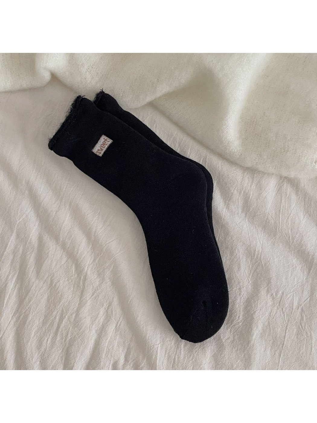 Black ribbed crew socks with a rolled cuff and small label patch