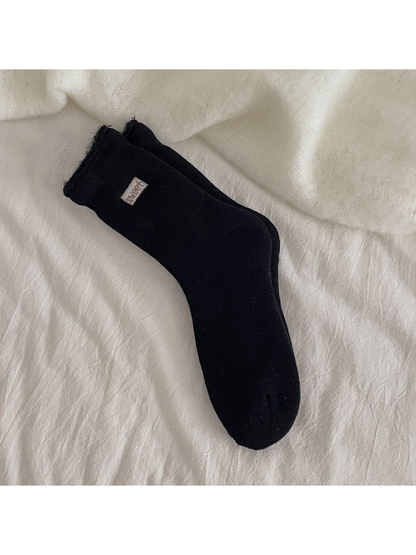 Black ribbed crew socks with a rolled cuff and small label patch