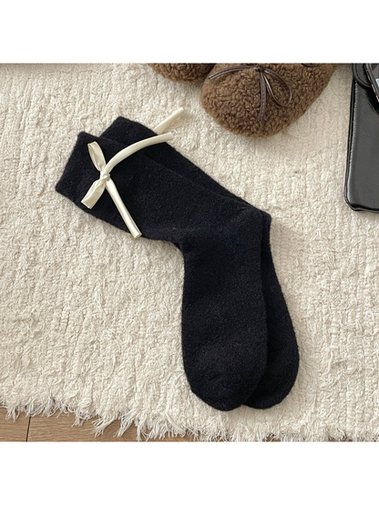 Black fuzzy crew socks with a cream ribbon bow