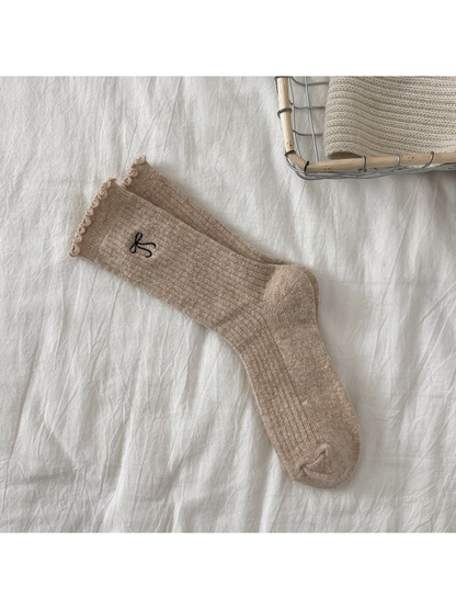 Beige ribbed crew socks with bow motif and ruffled cuffs
