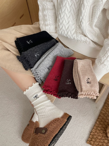 Multiple colors of bow-motif socks styled with ivory socks being worn