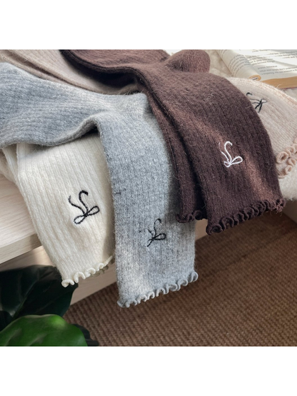 Close-up of ribbed texture, embroidered bow motifs and ruffled cuffs in four colors