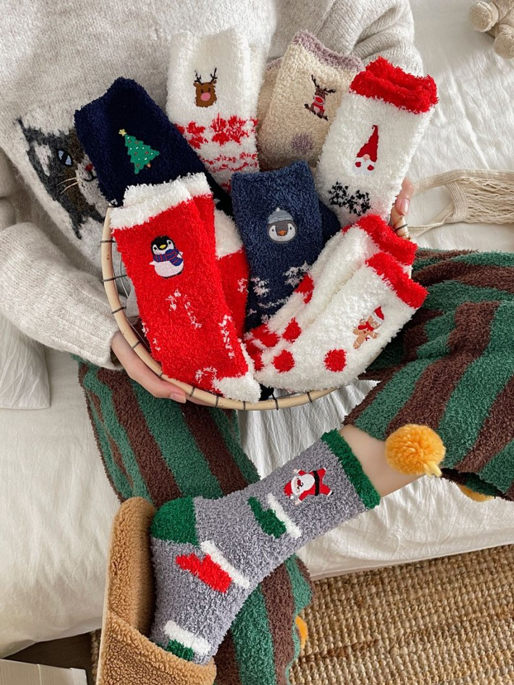 Assorted fuzzy holiday socks in a basket with gray Santa socks worn nearby