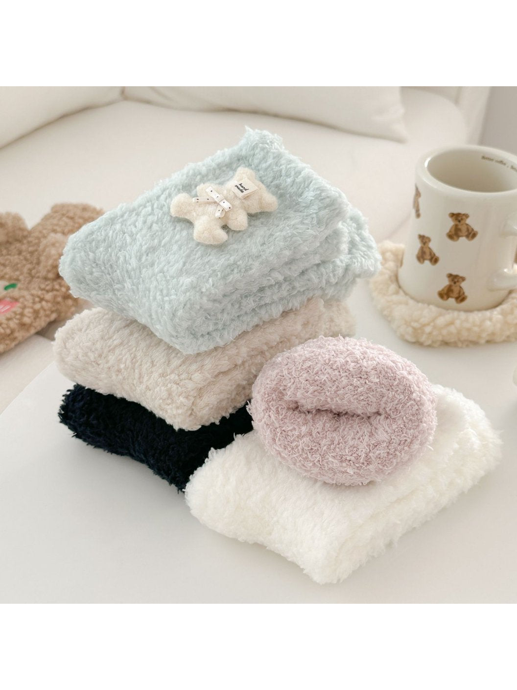Fuzzy socks stacked and rolled in assorted pastel and neutral colors