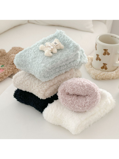 Fuzzy socks stacked and rolled in assorted pastel and neutral colors