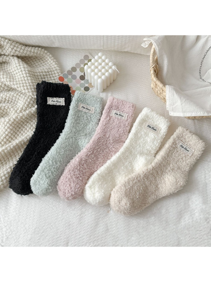 Fuzzy socks in black, mint green, dusty pink, ivory and beige displayed together