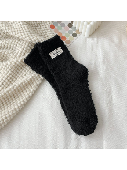 Black fuzzy socks with a rectangular label patch