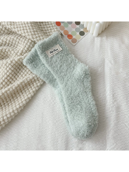Mint green fuzzy socks with a rectangular label patch