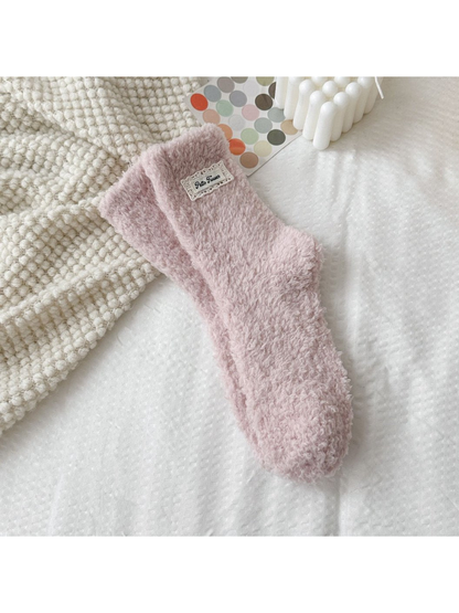 Dusty pink fuzzy socks with a rectangular label patch