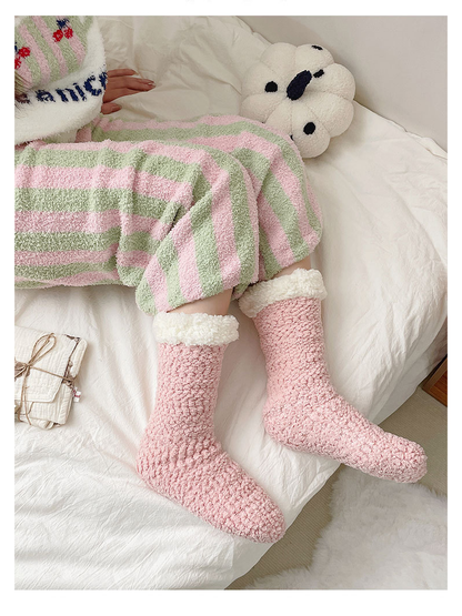 Light pink fuzzy crew socks worn while reclining on a bed