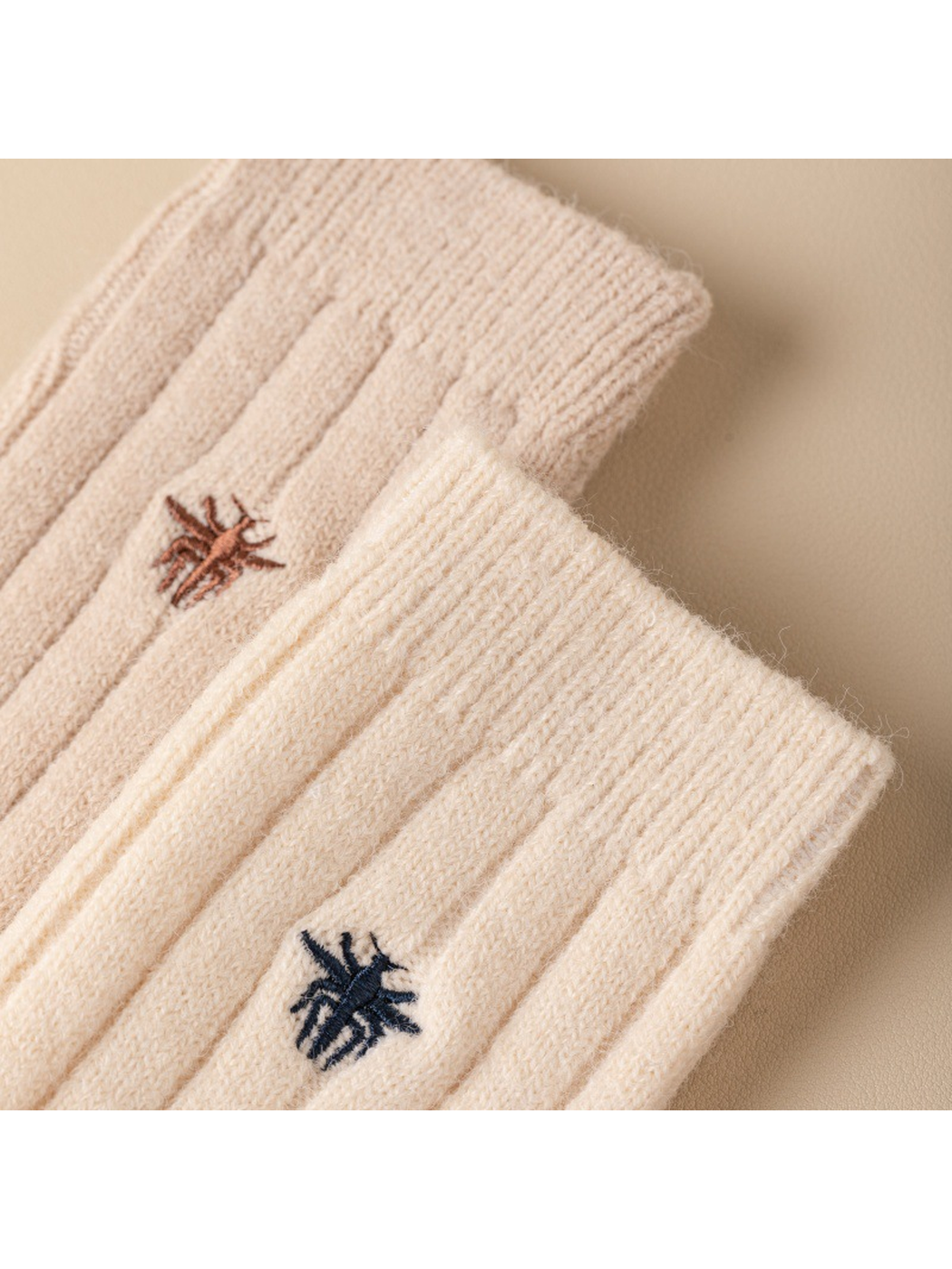 Close-up of embroidered insect motifs between raised sock ribs
