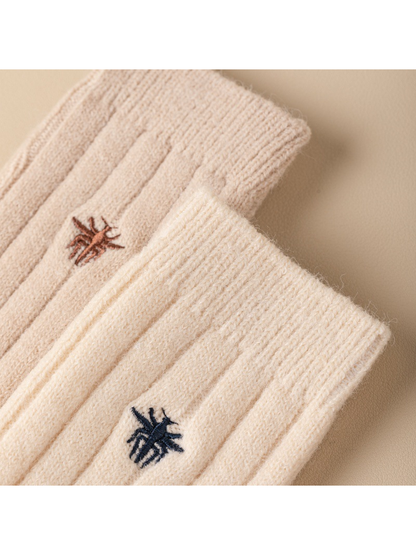 Close-up of embroidered insect motifs between raised sock ribs