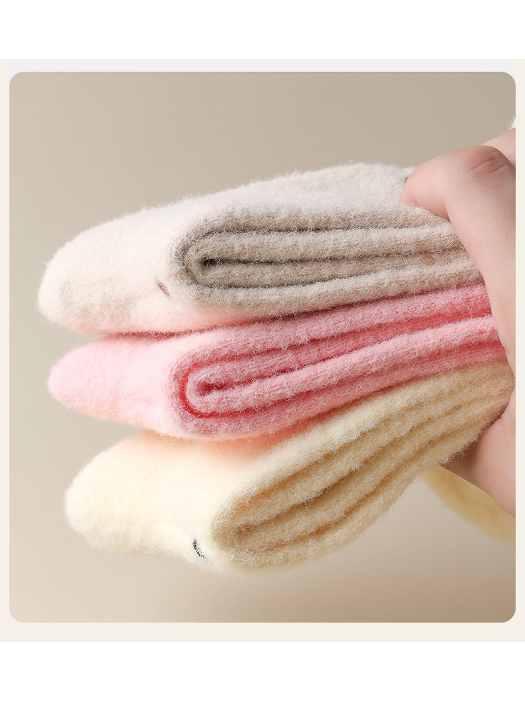 Close-up of beige, pink and pale yellow fuzzy socks folded in layers