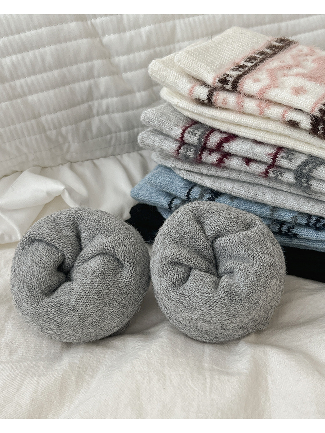 Rolled gray socks with folded patterned color variants in the background