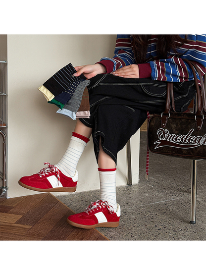Ivory striped crew socks worn with red sneakers while additional colors are held
