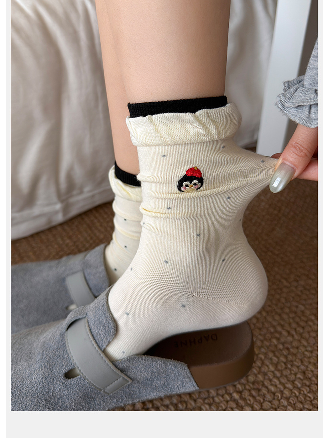 Close-up of an ivory dotted crew sock with character embroidery and ruffled cuff