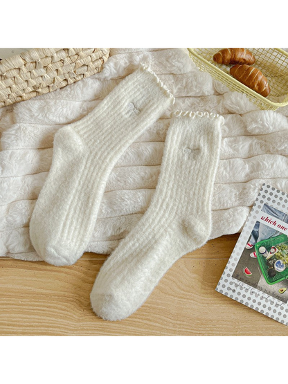 Ivory fuzzy ribbed socks with ruffled cuffs and bow motifs