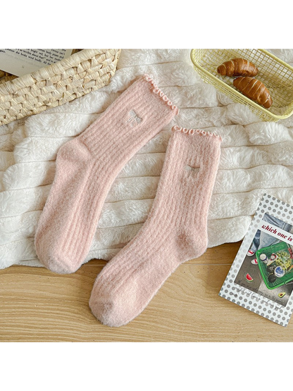 Light pink fuzzy ribbed socks with ruffled cuffs and bow motifs