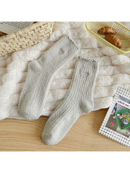 Light gray fuzzy ribbed socks with ruffled cuffs and bow motifs