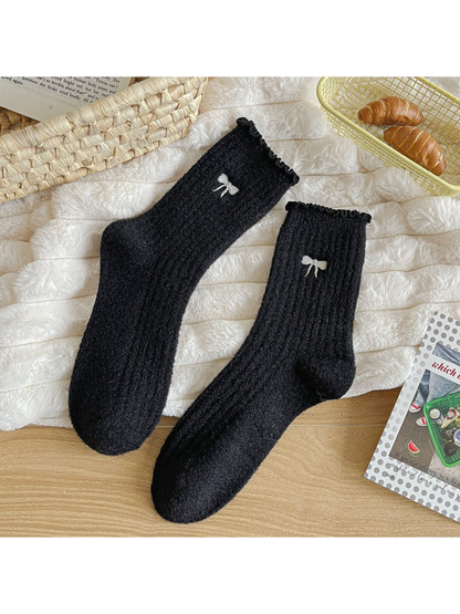 Black fuzzy ribbed socks with ruffled cuffs and bow motifs