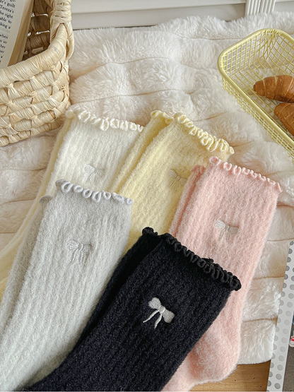Close-up of ruffled cuffs and embroidered bow motifs in five colors