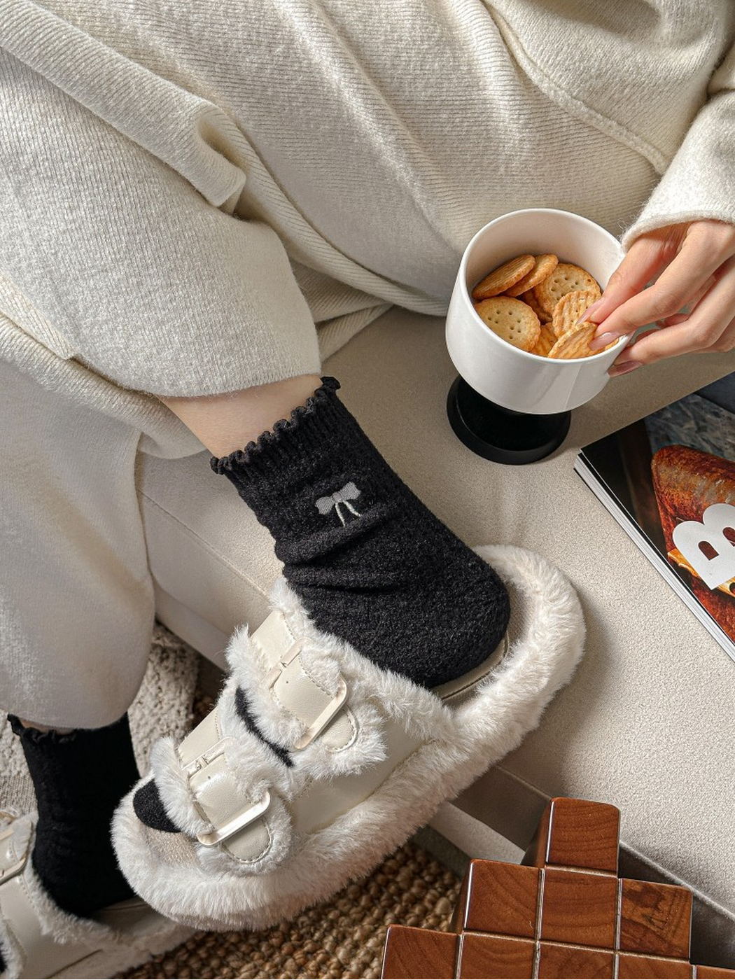 Black socks worn with plush buckle slippers in a seated setting
