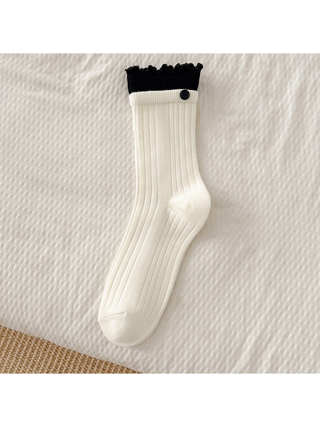 White ribbed crew sock with black ruffle cuff and button accent