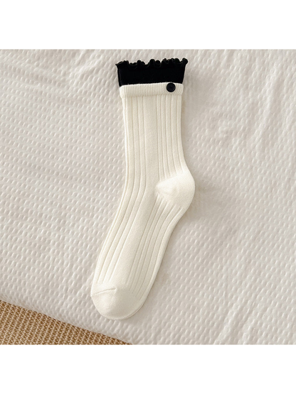 White ribbed crew sock with black ruffle cuff and button accent