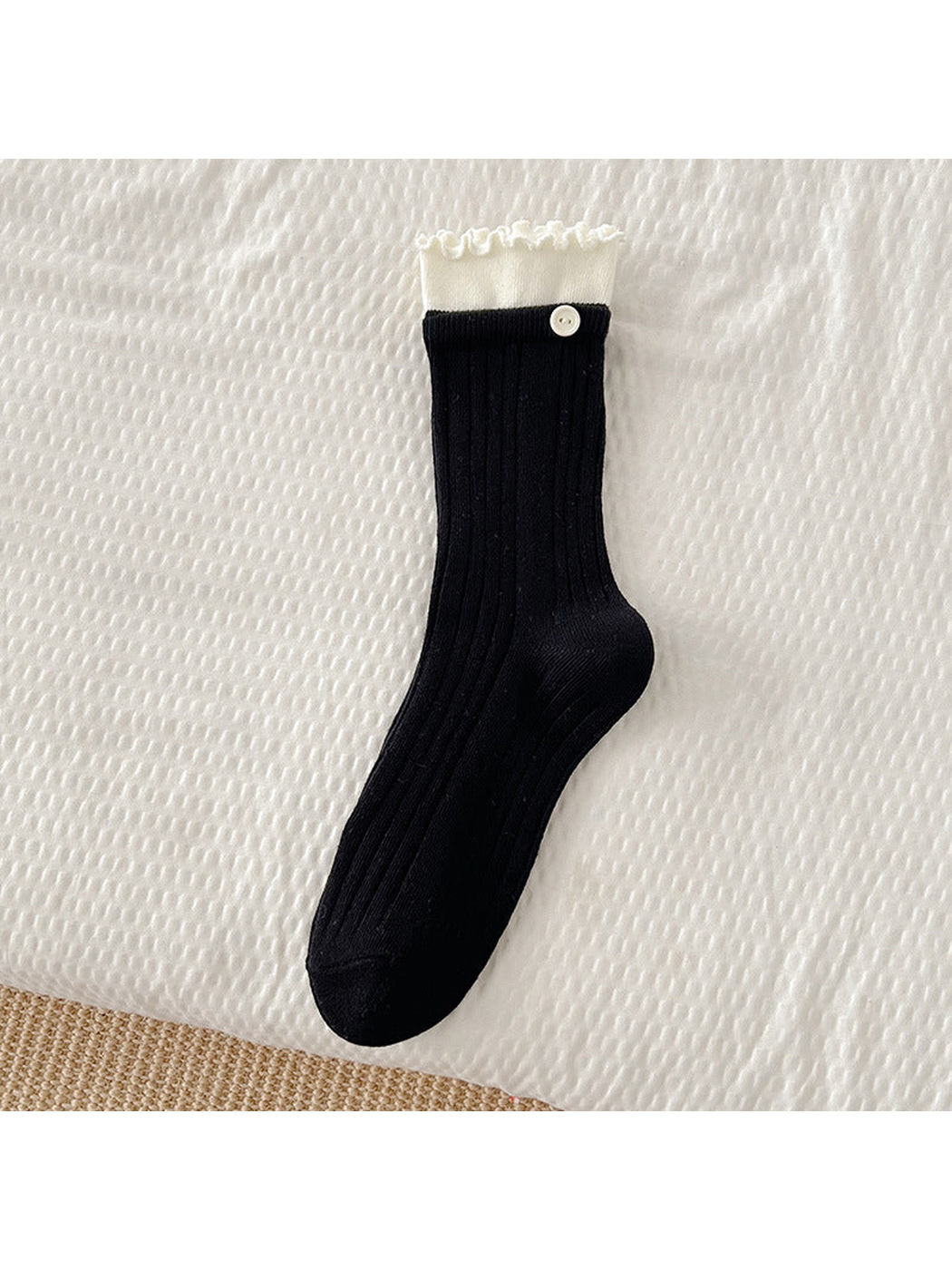 Black ribbed crew sock with white ruffle cuff and button accent