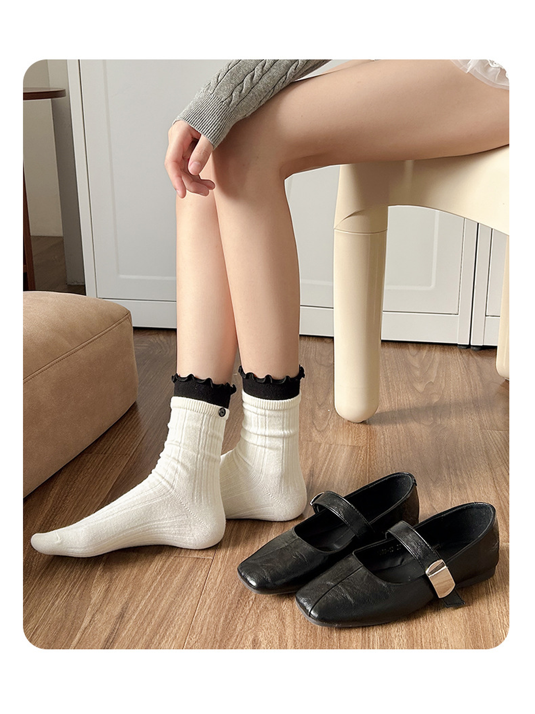 White ribbed socks with black ruffle cuffs displayed beside black flats