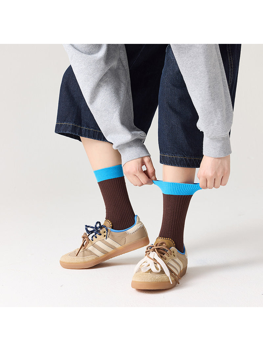 Brown ribbed socks with bright blue cuffs shown being stretched
