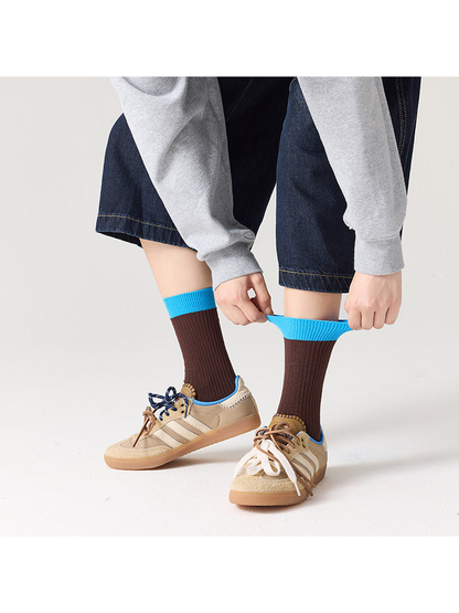 Brown ribbed socks with bright blue cuffs shown being stretched