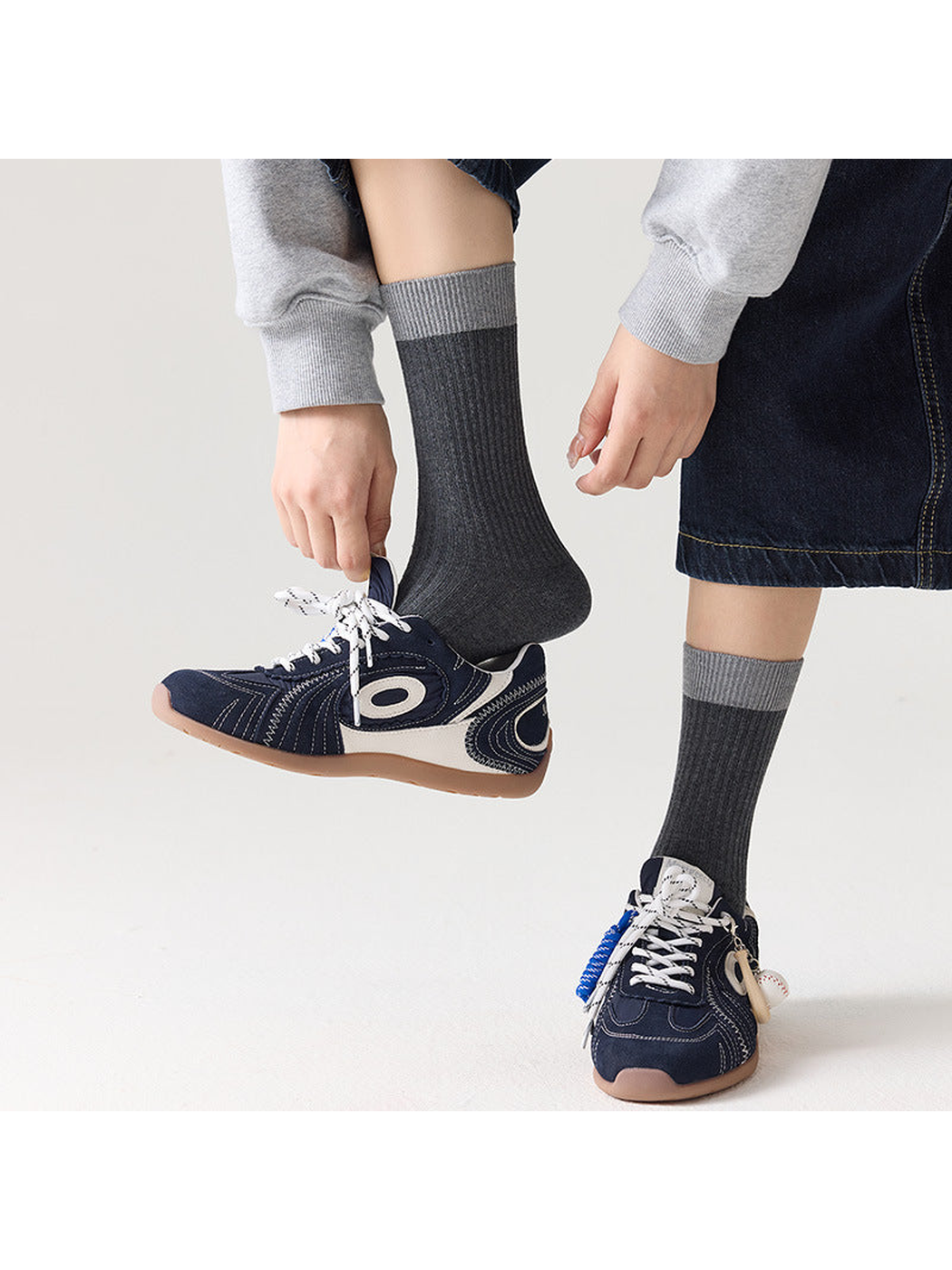 Dark gray ribbed socks with light gray cuffs styled with sneakers