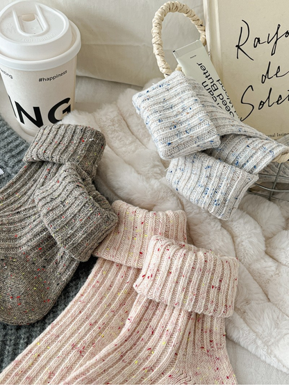 Close-up of folded ribbed cuffs in gray, ivory and pink