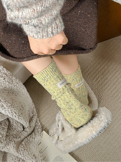 Pale yellow flecked crew socks worn with plush slippers