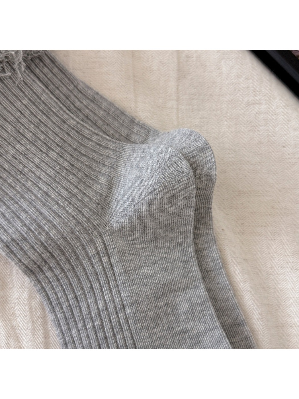 Close-up of the shaped heel and toe on light gray ribbed socks
