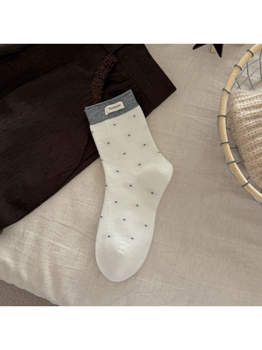 White polka-dot crew sock with a gray ribbed cuff and rectangular label