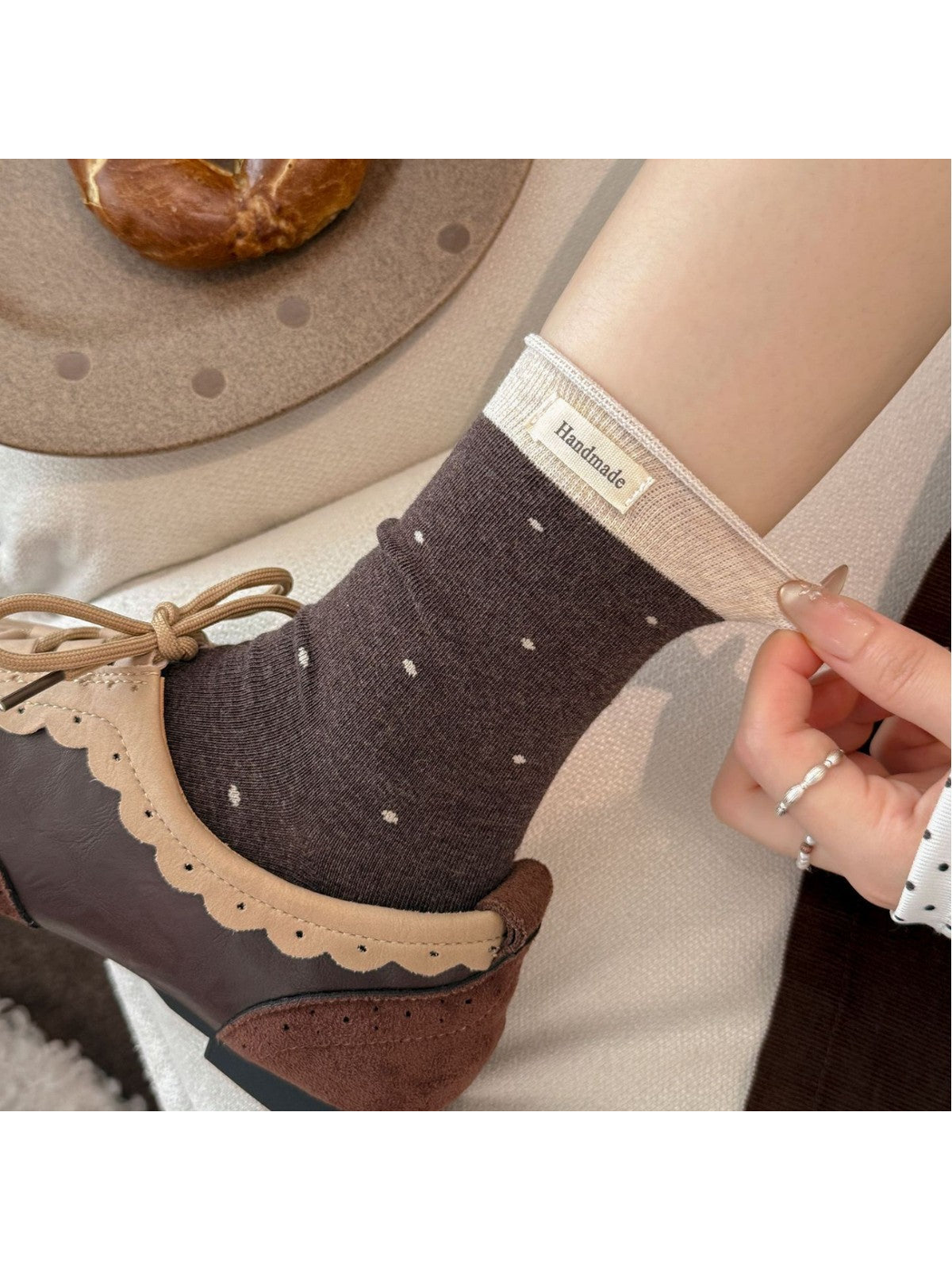 Close-up of dark brown polka-dot socks with a contrasting ribbed cuff and label