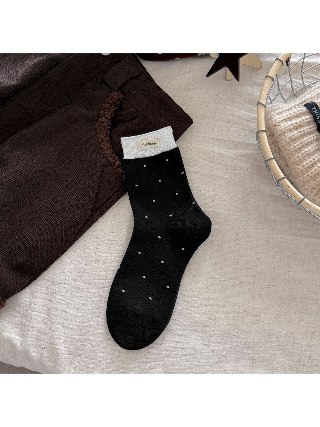 Black polka-dot crew sock with a white ribbed cuff and rectangular label
